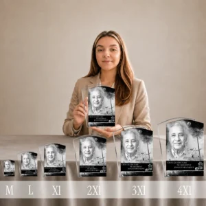 Femme présentant gamme de plaques funéraires stèle plexiglas argent, du format M au 4XL, avec portrait noir et blanc et texte gravé, thème campagne nature